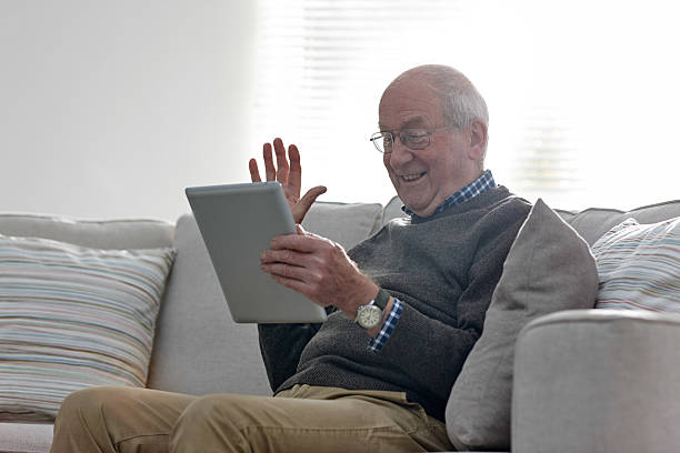 Senior man doing a video chat using digital tablet stock photo