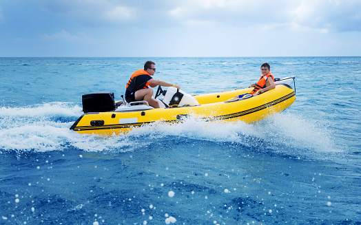 Father and son driving a Rigid inflatable speed boat in the caribbean