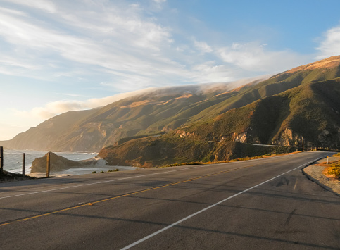 golden hour as the sun sets over the Pacific Ocean on the iconic Route 1, the Pacific Coast Highway in California