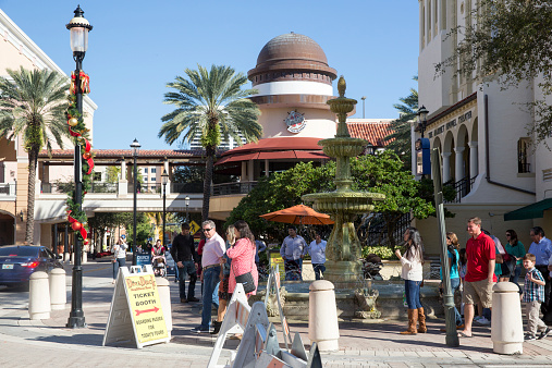 West Palm Beach, United States - December 14, 2014: People of all ages walk down a closed off street for the Family Fun Festival at City Place. Various tents are set up attracting festival goers. The entire area is decorated for the Chirstmas holidays, with decorations wrapped around poles and trees.   A theatre is situated on the street.  City Place is a major attraction for both tourists and resident Floridians. It often has street fairs. It is known for its many restaurants, retail shopping, and special events. Signs point visitors in the direction of special attractions and venues.