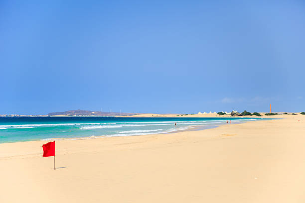 красный флаг на пляже boavista, кабо-верде - beach sand стоковые фото и изображения