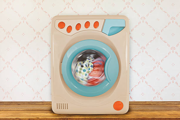 Vintage colorful washing machine in front of retro wallpaper