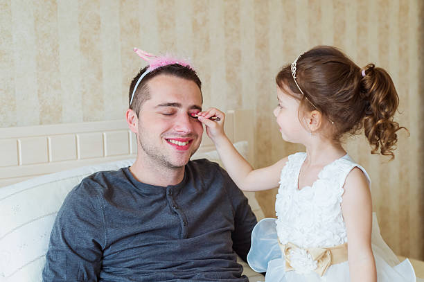 istock Cute girl putting on make up on her father 532328672