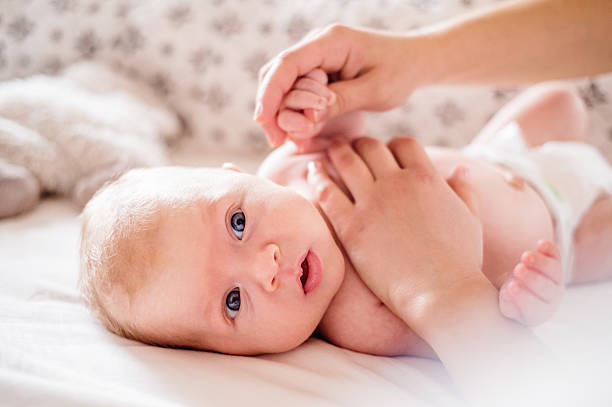 istock Baby boy lying on bed, held by his mother 532330278