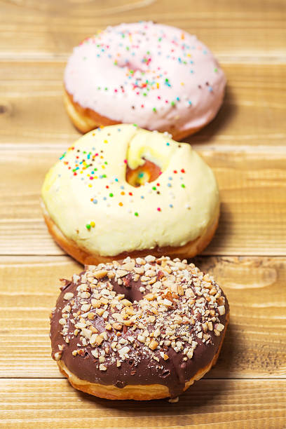 istock Three donut with colorful decor. Isolated on wooden background 532331328