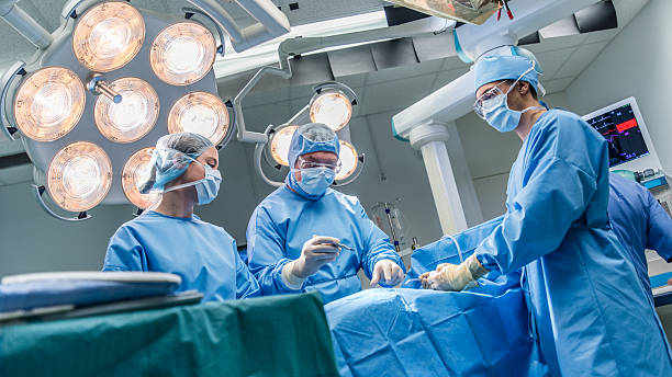 Surgeons in operating theatre Surgeons doing surgery in operating theatre. critical care photos stock pictures, royalty-free photos & images