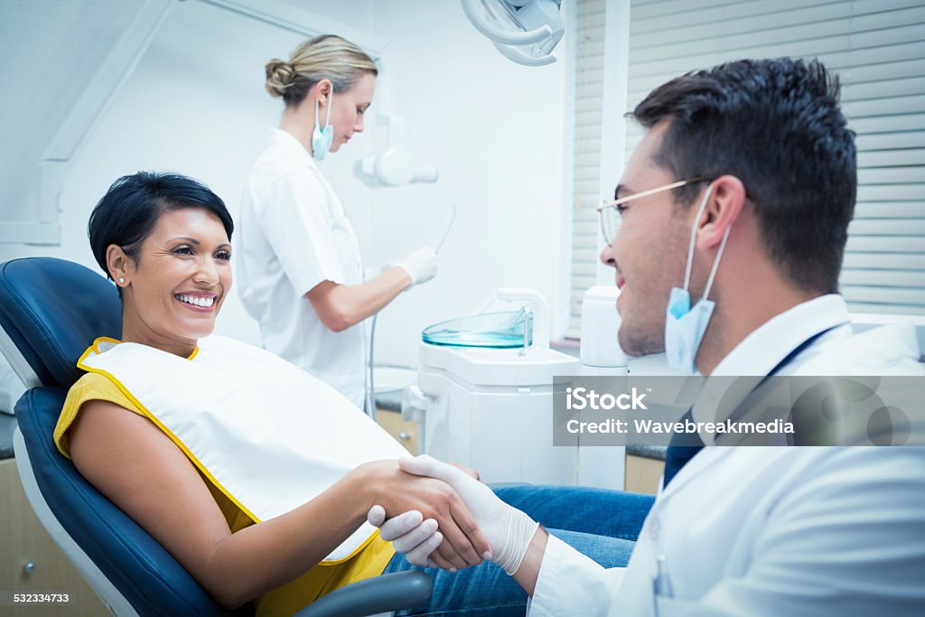 Male dentist shaking hands with woman Male dentist shaking hands with woman in the dentists chair Dentist Stock Photo