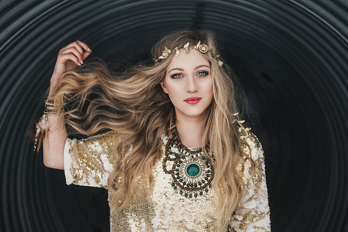 Young beautiful woman outdoors, in contemporary boho style. With long hair and a beautiful face.