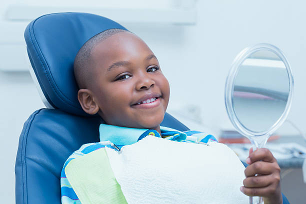 istock Boy holding at mirror in the dentists chair 532335037