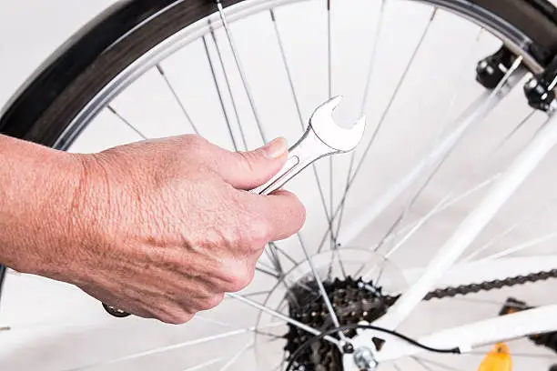 Woman hand repair bicycle whee with screw key - studio shoot