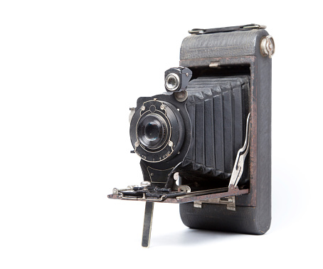 An old medium format camera with bellows lens from the 1940-50s on white background close up.