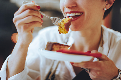 Smiling young woman is enjoying a piece of lemon cake