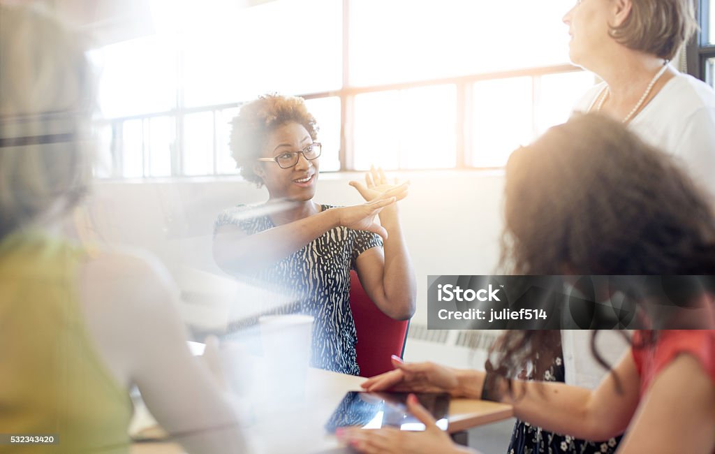 Unposed group of creative business people in an open concept Candid picture of a female boss and business team collaborating. Filtered serie with light flares, bokeh, warm sunny tones. Defocused Stock Photo