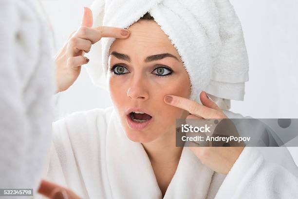 Worried Woman Looking At Pimple On Face Stock Photo - Download Image Now - Acne, Adult, Beauty Treatment