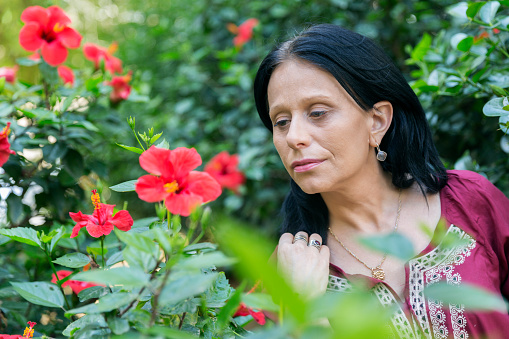 Mature brunette woman looking at blooming plant. Portrait