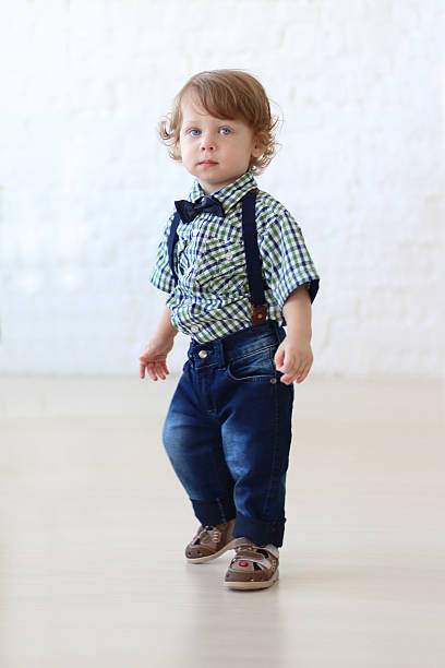 istock Little handsome curly boy in jeans stands in room 532347244