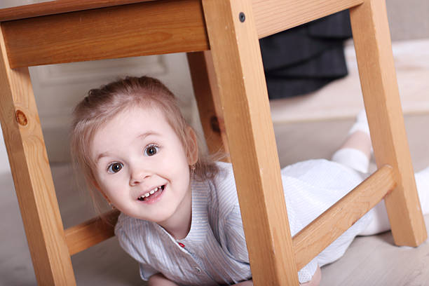 istock Little cute blond girl on floor under stool 532348840