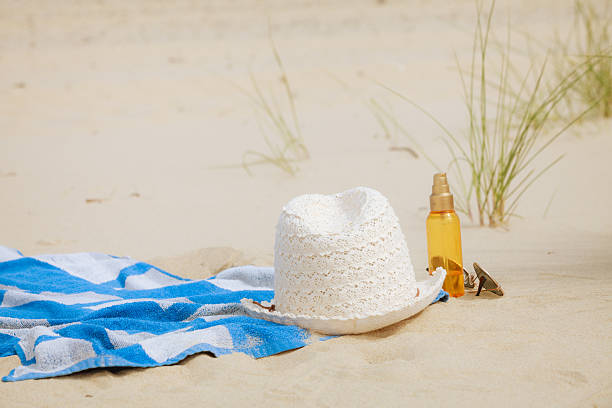 istock Beach set hat and sunscreen lotion lying on sand 532349158