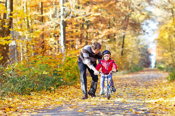 istock Little kid boy and father with bicycle in autumn forest 532349196