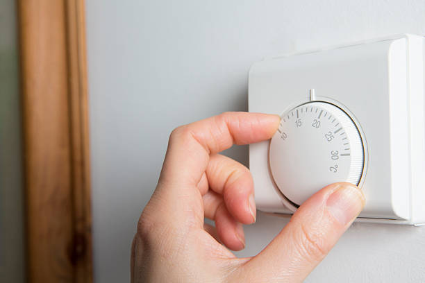 primer plano de mujer manos el termostato de calefacción central - termostato fotografías e imágenes de stock