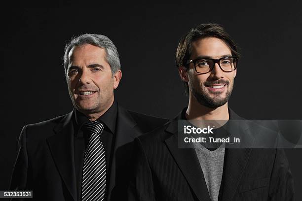 Senior Businessman And Young Businessman Smiling Standing Side By Side Stock Photo - Download Image Now