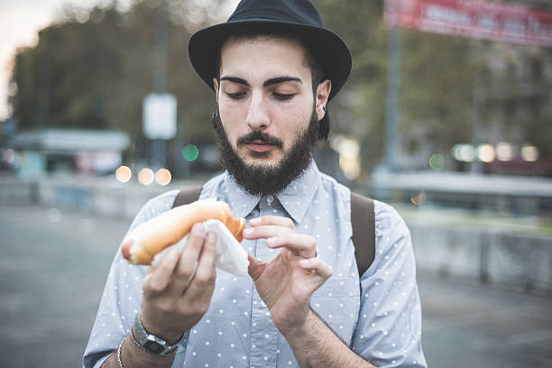 istock young handsome hipster gay modern man eating hot dog 532354385