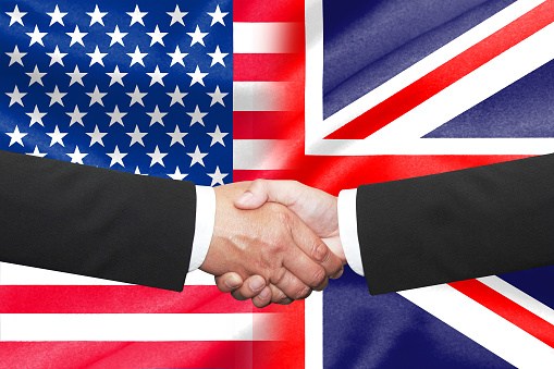 two businessmen shakehand over united kingdom and america national flag