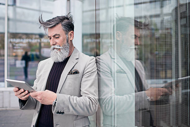 Senior businessman using digital tablet in office building Senior businessman using digital tablet in office building. stars in your eyes stock pictures, royalty-free photos & images