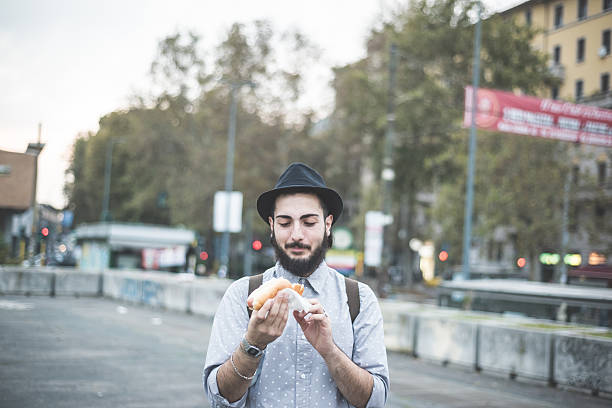 istock young handsome hipster gay modern man eating hot dog 532355457