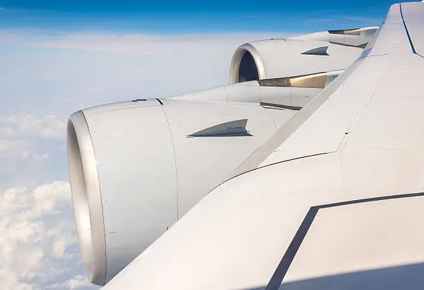 Wing with engines of Airbus A380 airliner flying over clouds