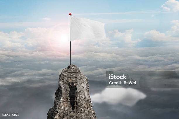 Businessman Climbing On Peak With Blank Flag And Sunlight Clouds Stock Photo - Download Image Now