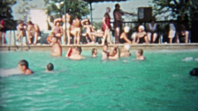 1959: People of all ages playing in public pool during a hot summer day.