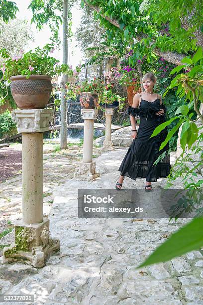 Elegant Woman In Black Evening Dress Standing In Garden Stock Photo - Download Image Now