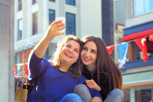 Beautiful girls taking their self portrait with their cell phone on shopping day.