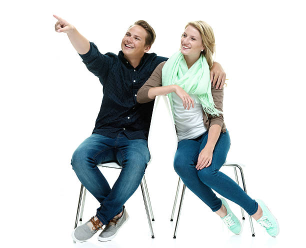 istock Cheerful couple on chair & pointing away 532379595