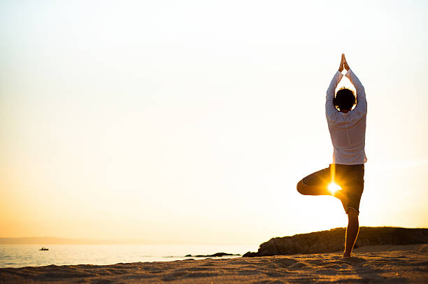 Practicing yoga and meditation in summer on beach in sunset