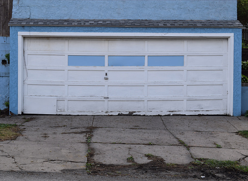 A garage with busted wood doors, peeling paint