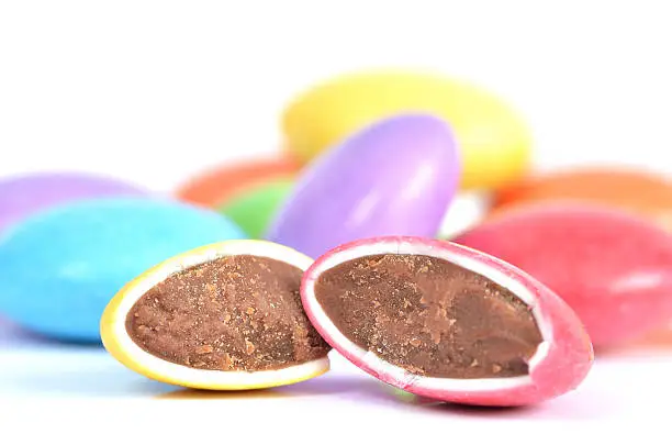 Halved red and yellow smarties with chocolate filling and blue, purple, yellow smarties in background