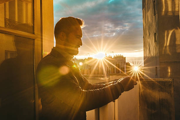 istock bearded man holding smartphone at opened window  in Paris 532392304