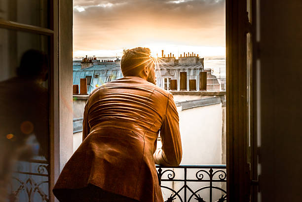 bearded man looking out of Paris window at sunset