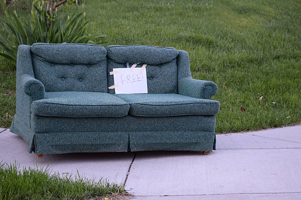 Free Couch on a Sidewalk A sofa placed on the sidewalk with a sign marking it free for pick up curb photos stock pictures, royalty-free photos & images