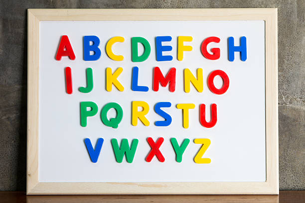 aimants alphabet en plastique sur tableau blanc - lettre magnétique photos et images de collection