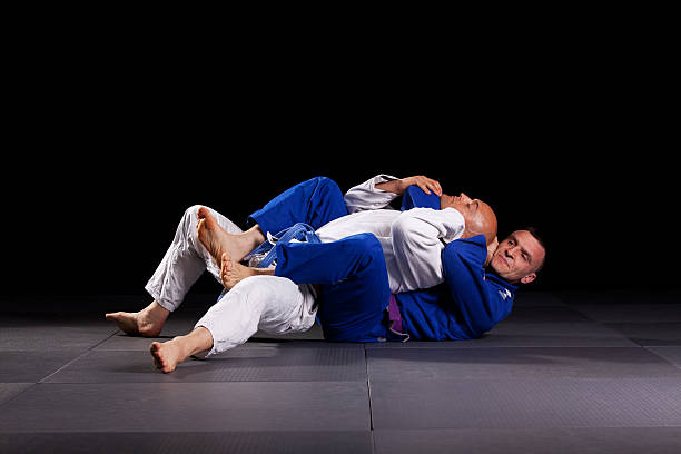 Brazilian jiu-jitsu martial arts Two jiujitsu wrestlers sparring in combat during the sport training. One fighter applying joint-lock and chokehold to defeat the opponent. Brazilian jiu-jitsu is martial art similar to judo, and mostly is focused on ground fighting. brazilian jiu jitsu photos stock pictures, royalty-free photos & images