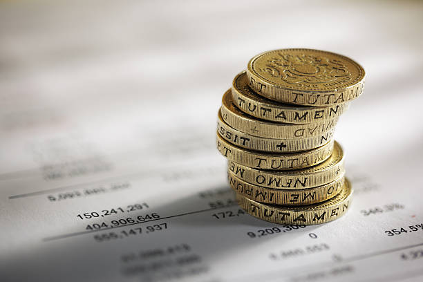 Stack of pound coins on financial figures Stack of pound coins on financial figures balance sheet one pound coin photos stock pictures, royalty-free photos & images