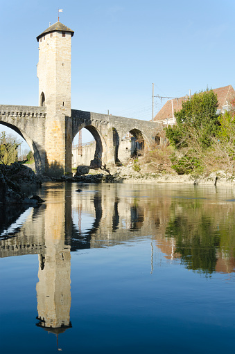 Old medieval fortified bridge across Gave de Pau River in Orthez reflecting in water, constructed by Gaston VII de Bearn, in XIII century when Orthez was the capital of Bearn