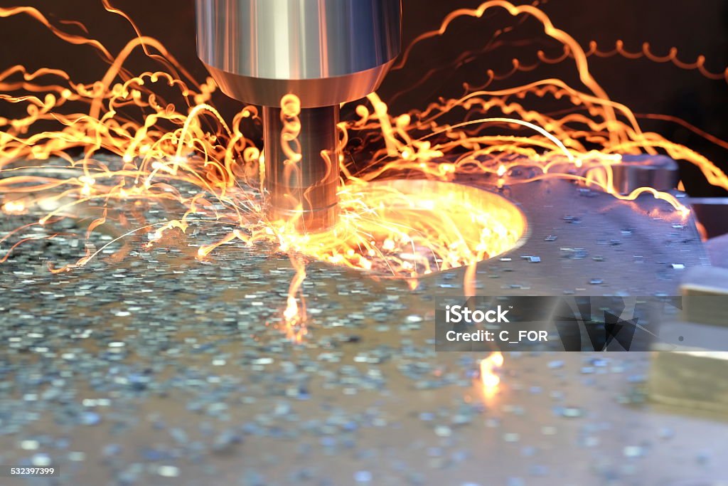 Milling machine Cutter in action during the drilling of the iron. Heavy duty machining drill bit moving into iron block. Note machine tool is rotating at high speed without refrigeration liquid. Milling Machine Stock Photo