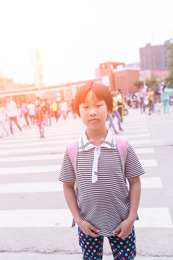 cute chinese girl elementary school aging 8, standing in the zebra crossing infront of school