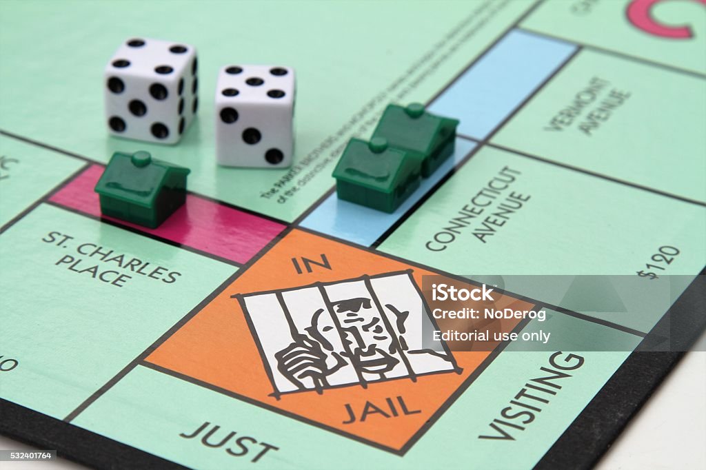 Monopoly game with Jail corner West Palm Beach, USA - August 15, 2013: A partial view of the Monopoly game board showing the Jail space. Dice and several houses are also placed near the Jail space. Monopoly is owned and manufactured by Hasbro. Monopoly Stock Photo