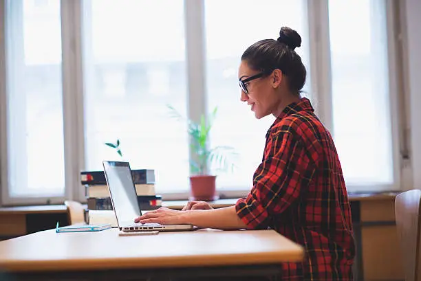 Photo of Young hipster girl working on laptop