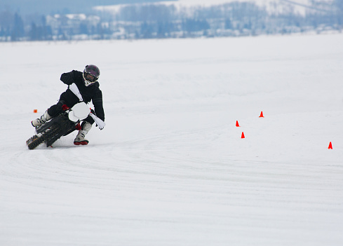 A man rides a corner at a winter motorcycle ice race on a frozen lake. 